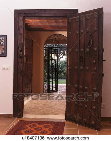 Stock Photograph - Open studded wooden door in Spanish hall. Fotosearch