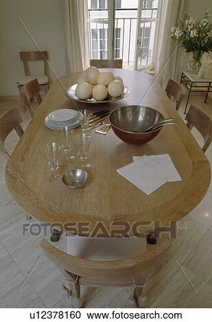 Stock Image - Pale wood table and chairs in French apartment dining room. Fotosearch