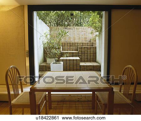 Pale wood table and chairs in front of large window in small modern dining room View Large Photo Image Stock Image - Pale wood table and chairs in front of large window in small modern dining room. Fotosearch