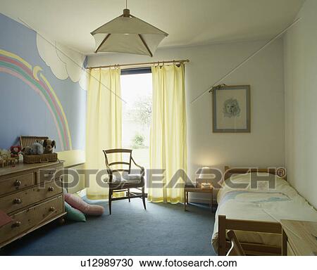 Pastel Yellow Curtains And Blue Carpet In Bedroom With Paint Effect Rainbow On Wall Stock Image