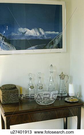 Stock Image - Picture above mahogany console table ith collection of antique glass decanters. Fotosearch