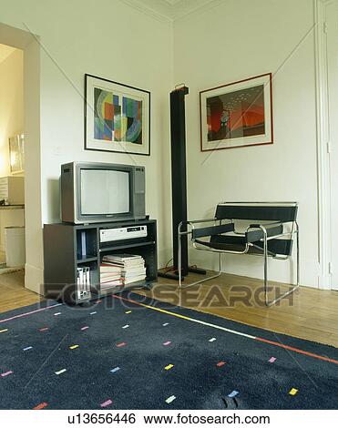 Stock Photograph - Pictures on wall above television Marcel Breuer Wassily chair in corner of modern living room with black abstract rug. Fotosearch