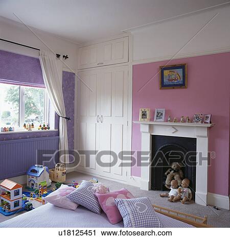 Stock Image - Pink and mauve child's bedroom with white fireplace. Fotosearch