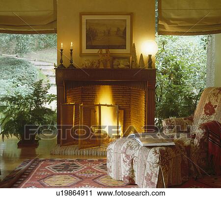 Pink armchair in front of fireplace between windows View Large Photo Image Stock Image - Pink armchair in front of fireplace between windows. Fotosearch