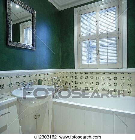Plantation shutters on window above bath in modern green bathroom View Large Photo Image Stock Image - Plantation shutters on window above bath in modern green bathroom. Fotosearch
