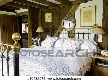 Quilts and floral bedlinen on antique brass bed in beamed cottage bedroom View Large Photo Image Stock Photography - Quilts and floral bedlinen on antique brass bed in beamed cottage bedroom. Fotosearch