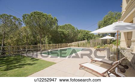 Stock Photo - Rear of villa in Southern Spain overlooking pool and woodland beyond.. Fotosearch