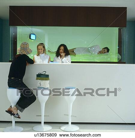 Receptionists and guest at desk in front of performance artist in aquarium at The Standard Hotel in Los Angeles View Large Photo Image Stock Photo - Receptionists and guest at desk in front of performance artist in aquarium at The Standard Hotel in Los Angeles. Fotosearch