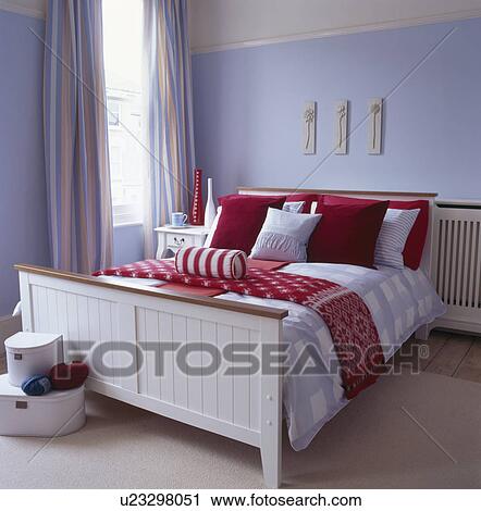 Red And White Cushions And Bedlinen On White Wooden Bed In