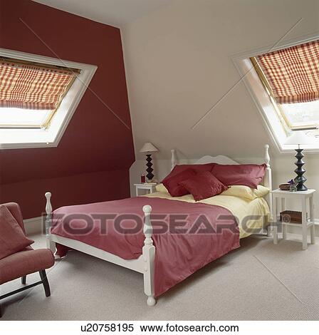 Stock Photography - Red and yellow linen on white bed in loft conversion bedroom with red wall. Fotosearch