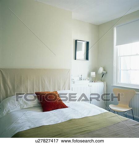 Stock Photo - Red cushion on bed in smll townhouse bedroom. Fotosearch