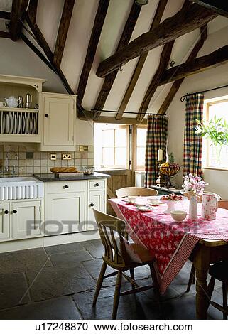 Red floral cloth on table in cream country kitchen with stone flooring and beamed apex ceiling View Large Photo Image Stock Image - Red floral cloth on table in cream country kitchen with stone flooring and beamed apex ceiling . Fotosearch
