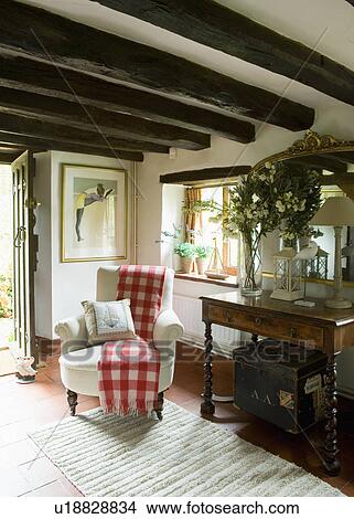 Red+white checked throw on white armchair in beamed country hall with antique console table View Large Photo Image Picture - Red+white checked throw on white armchair in beamed country hall with antique console table. Fotosearch