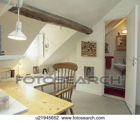 Simple table and chair in teenager's white attic bedroom with small ensuite bathroom View Large Photo Image Stock Image - Simple table and chair in teenager's white attic bedroom with small ensuite bathroom. Fotosearch