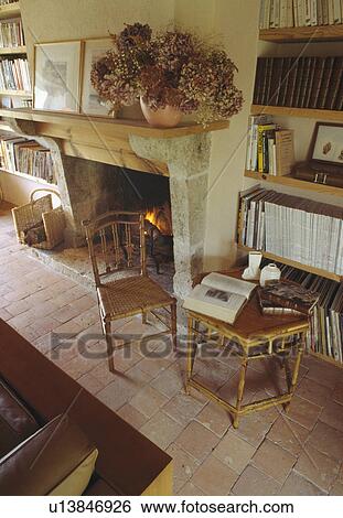 Stock Photograph - Small bamboo table and chair beside stone fireplace with lighted fire. Fotosearch
