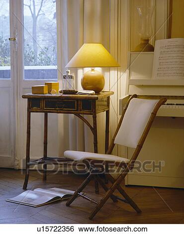 Small cream folding chair and antique table in French living room View Large Photo Image Stock Photograph - Small cream folding chair and antique table in French living room. Fotosearch