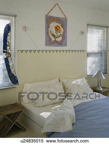 Stock Photography - Stained glass ornament on window in bedroom with painted border above bed. Fotosearch
