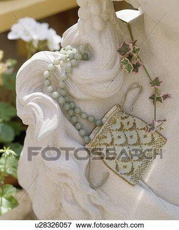Stock Photo - Still-Life of beaded handbag on marble statue. Fotosearch