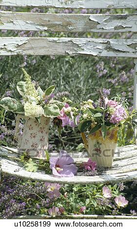 Still-life of fresh flowers in old jugs on dilapidated garden chair View Large Photo Image Stock Photo - Still-life of fresh flowers in old jugs on dilapidated garden chair. Fotosearch