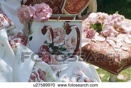 Stock Image - Still-life of pink roses in rose-patterned handbag on floral fabric. Fotosearch