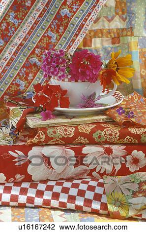 Still-life of red and pink flowers in teacup of pile of brightly coloured fabric View Large Photo Image Stock Image - Still-life of red and pink flowers in teacup of pile of brightly coloured fabric. Fotosearch
