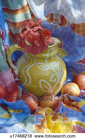 Stock Photo - Still-life of red geranium flower in yellow pottery jug with apples. Fotosearch