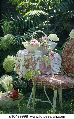 Still-life of rose-patterned cloth on table with patterned red chair in summer garden View Large Photo Image Stock Photo - Still-life of rose-patterned cloth on table with patterned red chair in summer garden. Fotosearch