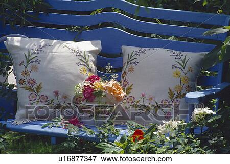 Stock Photo - Still-life of roses and embroidered cushions on blue garden bench. Fotosearch