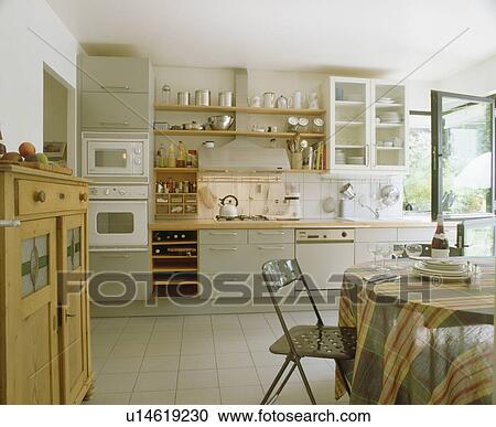 Striped cloth on table with metal chair in modern kitchen with white tiled floor and grey fitted units View Large Photo Image Stock Image - Striped cloth on table with metal chair in modern kitchen with white tiled floor and grey fitted units. Fotosearch