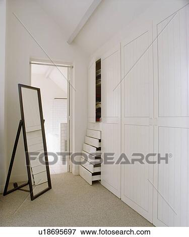 Tall Freestanding Mirror In Modern White Dressing Room With Fitted Stock Photo Tall Freestanding Mirror In Modern White Dressing Room With Fitted Wardrobe Fotosearch