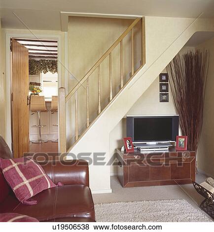 Stock Photo - Television on chest below staircase in cottage living room. Fotosearch