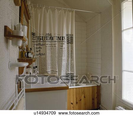 Stock Photo - The Times shower curtain on bath in small white bathroom. Fotosearch