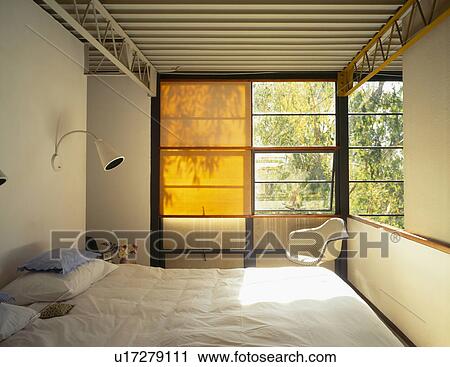 Stock Image - Wall lamp above bed and blind on window in Charles+Ray Eames bedroom at Pacific Palisades. Fotosearch