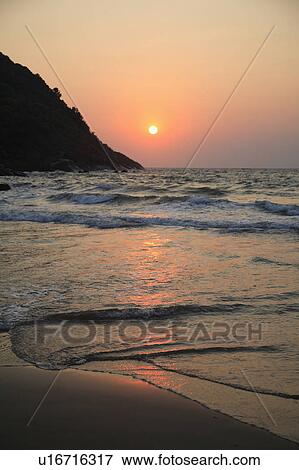 Stock Photo - Waves rolling onto deserted beach at sunset.. Fotosearch