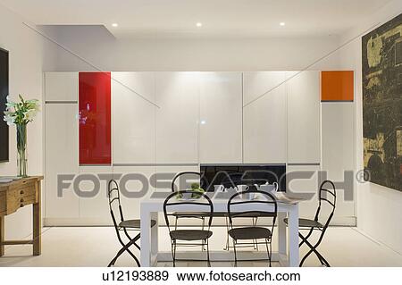 Stock Photo - Well lit minimalist kitchen with cupboard doors closed to hide contents and table and chairs.. Fotosearch