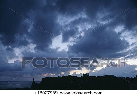 Stock Photo - Whitby Abbey and town silhoutted against dramatic black storm clouds and grey evening sky at Whitby in Yorkshire. Fotosearch