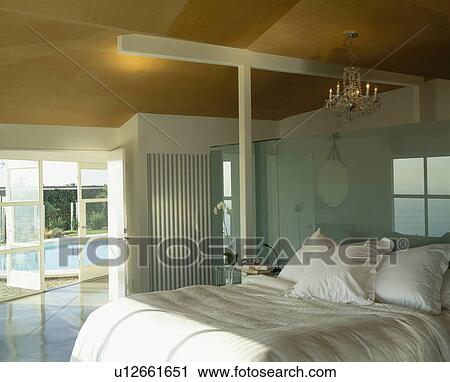 White bedlinen on bed in modern bedroom with glass doors open to swimming pool View Large Photo Image Stock Image - White bedlinen on bed in modern bedroom with glass doors open to swimming pool. Fotosearch