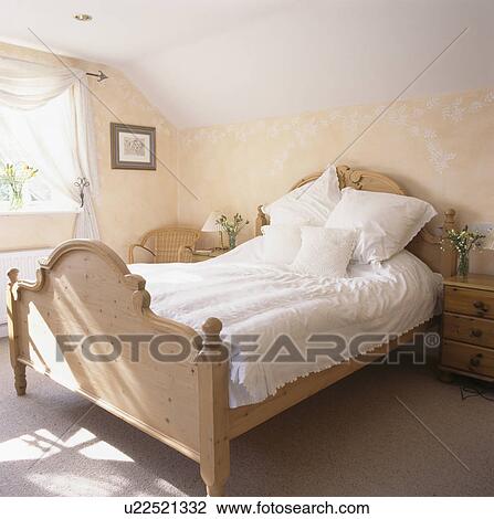 Stock Image - White bedlinen on pine bed in bedroom with stencilled wall. Fotosearch