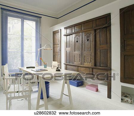 White chair and trestle table in country study with antique cupboard View Large Photo Image Stock Image - White chair and trestle table in country study with antique cupboard. Fotosearch