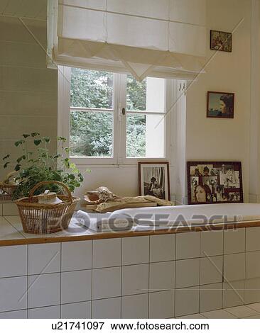 Stock Photo - White linen blind on window above bath with white tiled surround. Fotosearch