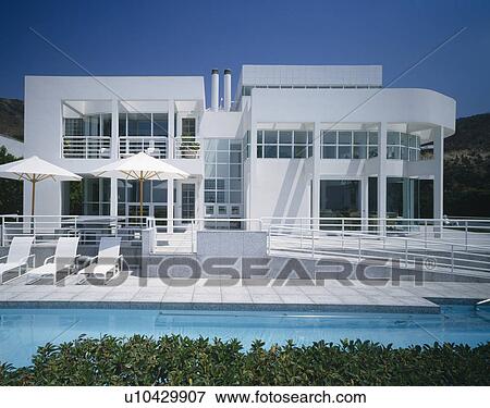 White umbrellas and sun-loungers on terrace beside swimming pool of modern white house on Californian coast View Large Photo Image Stock Photo - White umbrellas and sun-loungers on terrace beside swimming pool of modern white house on Californian coast. Fotosearch