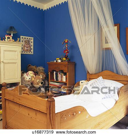 White voile drapes above child's pine sleigh bed in blue bedroom View Large Photo Image Stock Photo - White voile drapes above child's pine sleigh bed in blue bedroom. Fotosearch