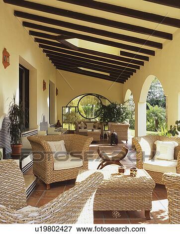 Stock Photo - Wicker armchairs and table on large veranda of Spanish villa. Fotosearch