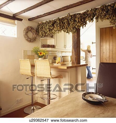 Woman in soft focus in cream cottage kitchen with hop bine View Large Photo Image Stock Photo - Woman in soft focus in cream cottage kitchen with hop bine. Fotosearch