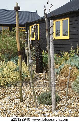 Wooden pole sculptures in gravel garden in front of Derek Jarmans black wooden beach house at Dungeness in Kent View Large Photo Image Stock Image - Wooden pole sculptures in gravel garden in front of Derek Jarmans black wooden beach house at Dungeness in Kent. Fotosearch
