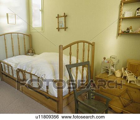 Wooden storage drawers below wooden bed in child's bedroom with miniature furniture on pine chest-of-drawers View Large Photo Image Stock Photograph - Wooden storage drawers below wooden bed in child's bedroom with miniature furniture on pine chest-of-drawers. Fotosearch
