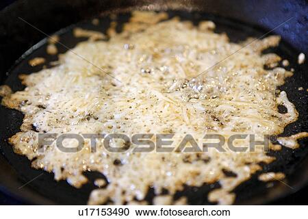 Stock Image - Melting Parmesan Cheese in Pan. Fotosearch