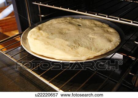 Stock Photo - Pizza Base in the oven. Fotosearch