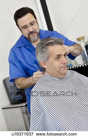 Barber cutting hair of mature male customer View Large Photo Image Stock Photo - Barber cutting hair of mature male customer. Fotosearch