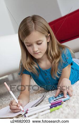 Blond girl doing homework while lying down on rug View Large Photo Image Stock Image - Blond girl doing homework while lying down on rug. Fotosearch